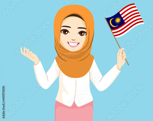 Beautiful Malaysian muslim woman wearing orange hijab holding Malaysia flag and presenting hand