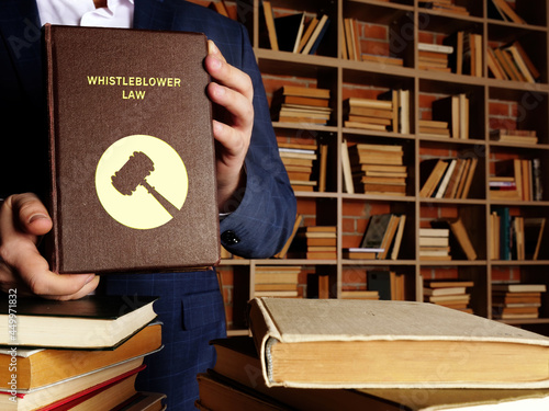 Jurist holds WHISTLEBLOWER LAW book. As a whistleblower you're protected by law - you should not be treated unfairly or lose your job because you 'blow the whistle' photo