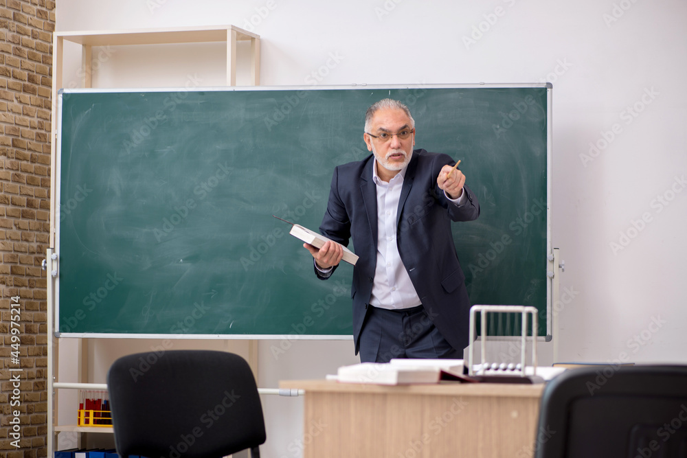 Old male teacher in front of blackboard Old male teacher in front of blackboard