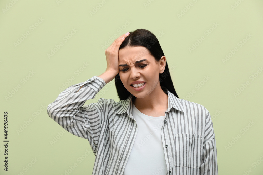 Woman suffering from migraine on light green background Woman suffering from migraine on light green background
