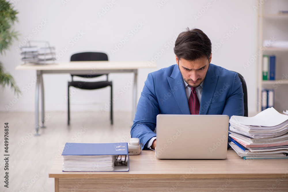 Young male employee and too much work in the office Young male employee and too much work in the office