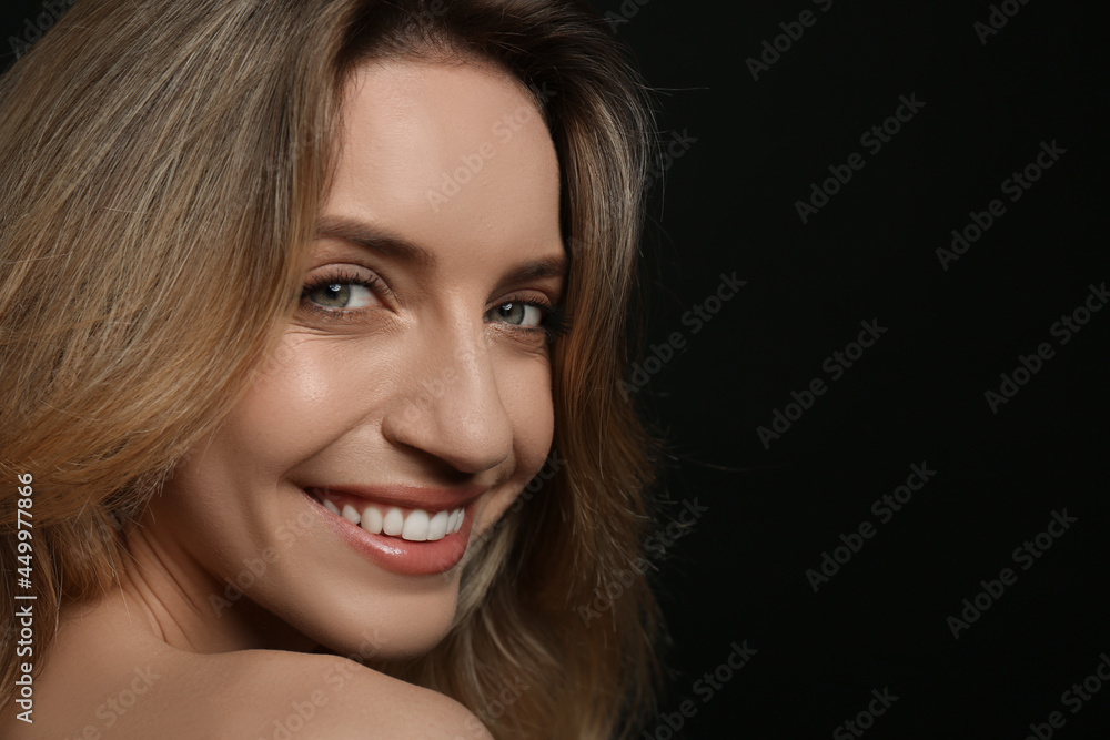Portrait of happy young woman with beautiful blonde hair and charming smile on black background, closeup. Space for text Portrait of happy young woman with beautiful blonde hair and charming smile on black background, closeup. Space for text