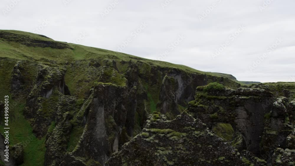 Medium shot with a left to right pan over the top of the canyon cliffs in Fjadrargliufur. A popular tourist spot in Iceland. Medium shot with a left to right pan over the top of the canyon cliffs in Fjadrargliufur. A popular tourist spot in Iceland.