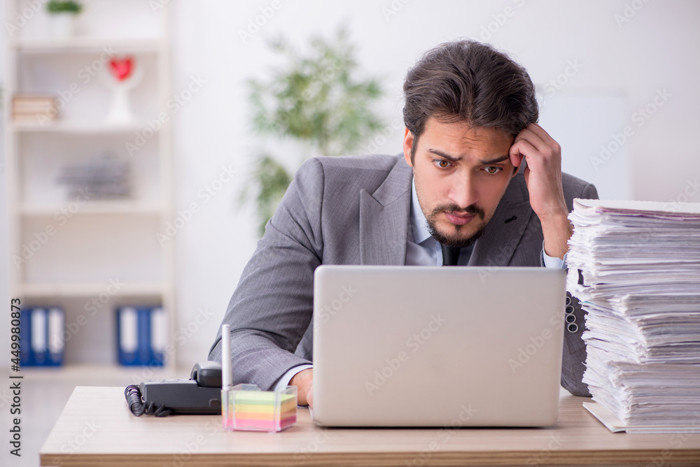 Young male employee and too much work in the office Young male employee and too much work in the office