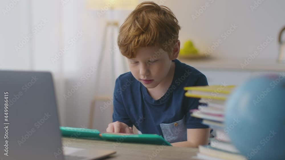 Time to study. Cute little redhead boy reading book at home, preparing to school, learning foreign language distantly Time to study. Cute little redhead boy reading book at home, preparing to school, learning foreign language distantly