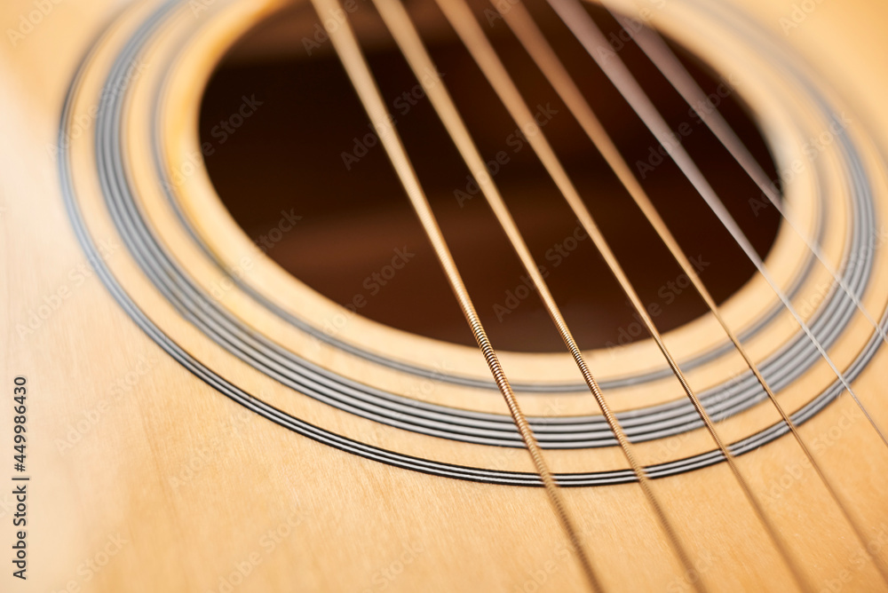 Detail of the body of a light wood guitar, the soundhole and strings. Detail of the body of a light wood guitar, the soundhole and strings.