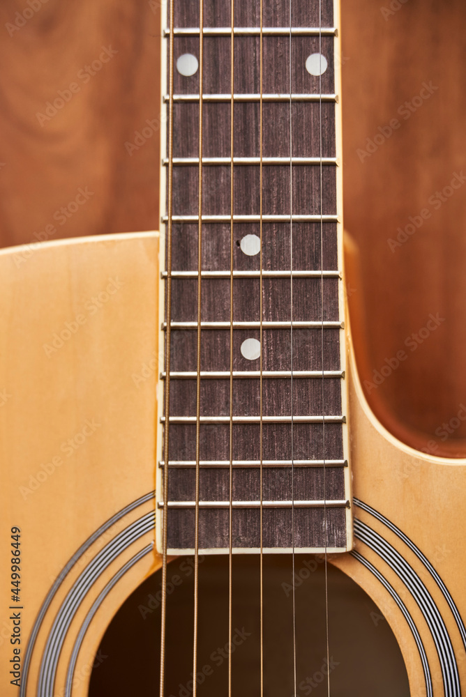 Detail of the body of a light wood guitar, soundhole, fretboards and strings.
