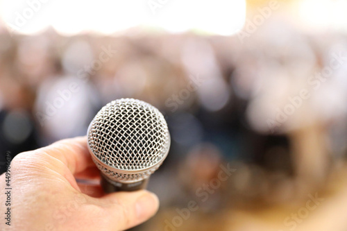 A microphone up very close with a hand about to clasp it in preparation of speaking to a large audience. Fear of public speaking concept.