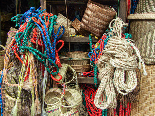 Halters and bridles, different ropes in blue, green and red colors along with wicker natural baskets and mats for sale at artisan market in Cuenca, Ecuador.