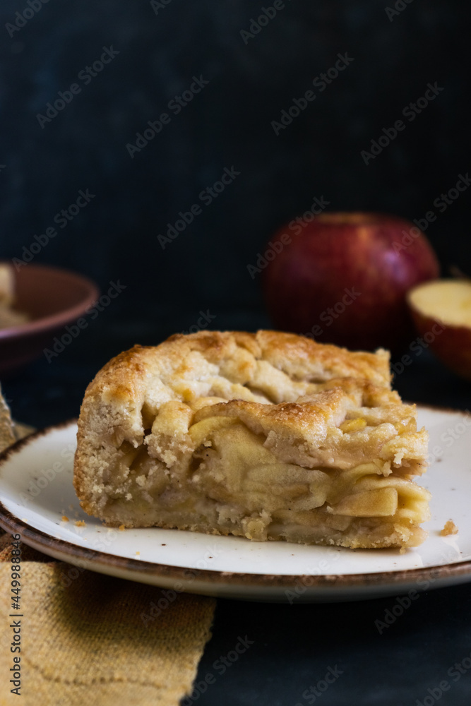 Slice of homemade apple pie with dark background. Apples and cloth on the background. Close up. Dark mood, rustic, fresh. Slice of homemade apple pie with dark background. Apples and cloth on the background. Close up. Dark mood, rustic, fresh.