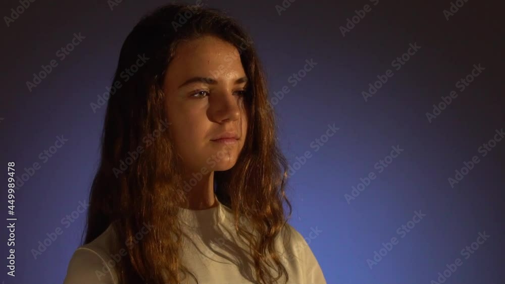 Close-up Portrait of a serious and smiling teenager curly brunette girl with Projector Reflection on her face. Slow motion, copy space Close-up Portrait of a serious and smiling teenager curly brunette girl with Projector Reflection on her face. Slow motion, copy space
