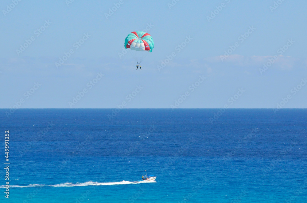 Boat pulls parasailing couple with blue skies and a bluer ocean in background. Boat pulls parasailing couple with blue skies and a bluer ocean in background.