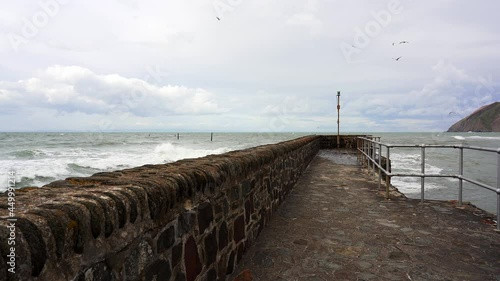 Waves crash around the harbor wall and sea defences of Lynmouth on a windy day. Devon, England, UK photo