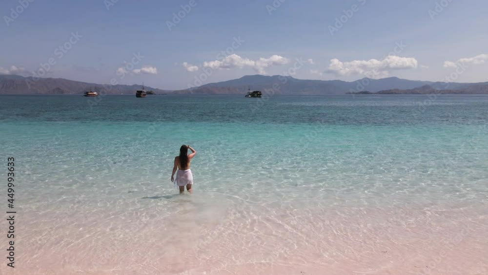 Female Tourist At The Shore Watches The Traditional Boats Sailing At The Indonesian Ocean. aerial Female Tourist At The Shore Watches The Traditional Boats Sailing At The Indonesian Ocean. aerial