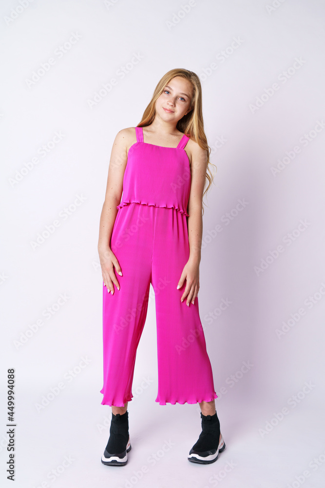 Beautiful girl teenager posing in a pink jumpsuit on a white background. Stylish and youthful bright clothes for a young professional fashion model Beautiful girl teenager posing in a pink jumpsuit on a white background. Stylish and youthful bright clothes for a young professional fashion model