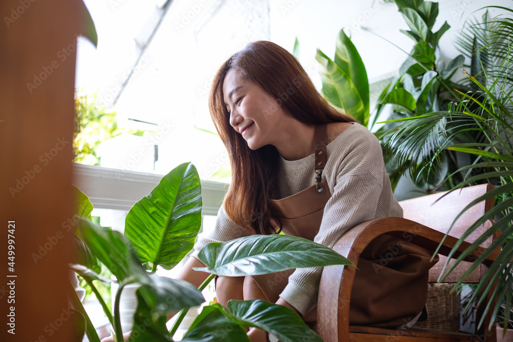 Portrait image of a beautiful young asian woman holding and taking care of houseplants at home Portrait image of a beautiful young asian woman holding and taking care of houseplants at home