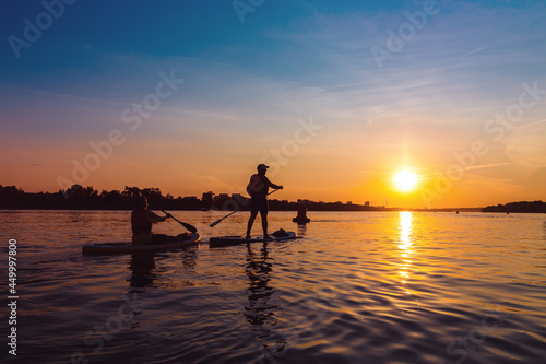 Silhouette paddle board surfer at sunset. Man boating ride on city river. Concept of outdoor activities