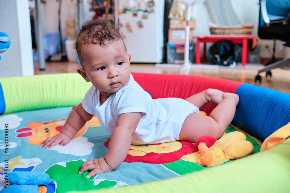 Cute baby boy lying on his tummy on a colorful play mat at home. Cute baby boy lying on his tummy on a colorful play mat at home.