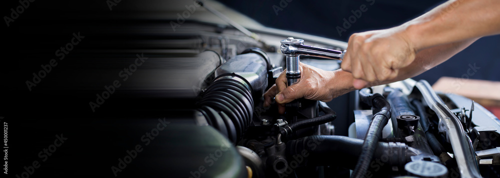 The mechanic works on the engine of the car in the garage, car repair service.
