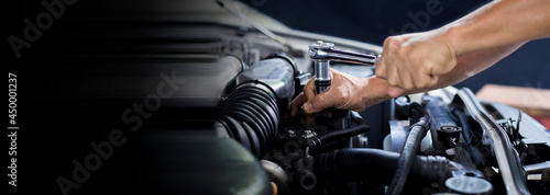 The mechanic works on the engine of the car in the garage, car repair service.