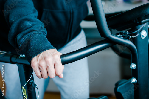 Elderly woman's hands on the handles of an electric treadmill. Health care