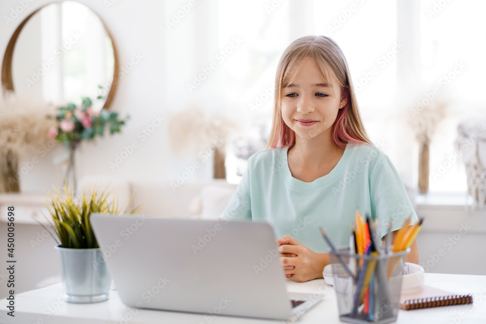 Happy little girl pupil using laptop at home Happy little girl pupil using laptop at home