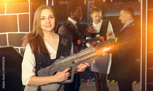 Nice woman and her colleagues on background having corporative entertainment in laser tag room