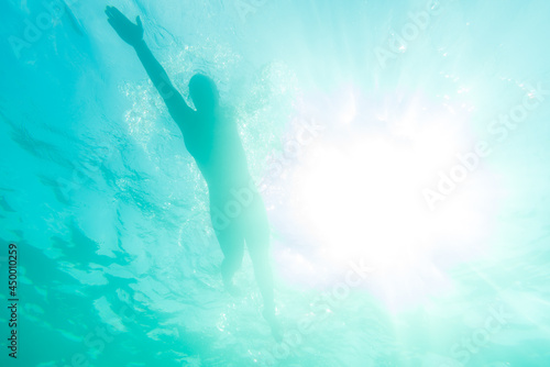 Silhouette of an athlete swimming in beautiful blue water at a sunny day