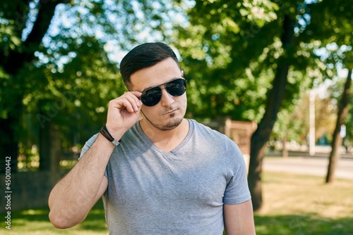 portrait of a young caucasian man in sunglasses on the background of trees