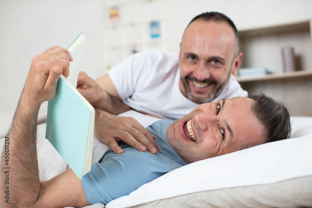 Fototapeta premium happy gay couple lying on bed at home