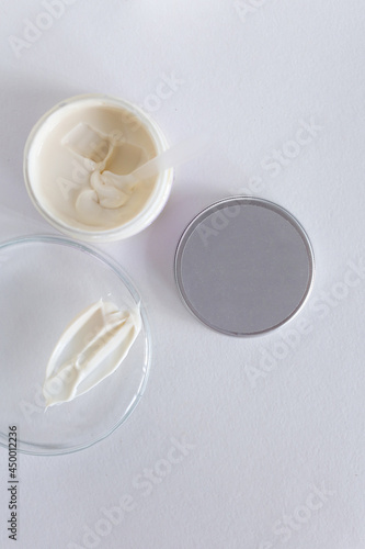 Moisturizing cosmetic cream stands on neutral background with milk splash