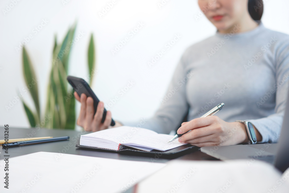 Office work concept a female officer using a mobile phone to check meeting agenda for tomorrow Office work concept a female officer using a mobile phone to check meeting agenda for tomorrow
