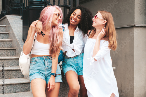 Three young beautiful smiling hipster female in trendy summer clothes.Sexy carefree multiracial women posing on the street background.Positive models having fun in sunglasses. Cheerful and happy