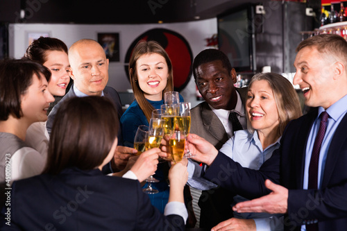 International group of glad positive businesspeople toasting with champagne, having fun at office party in nightclub