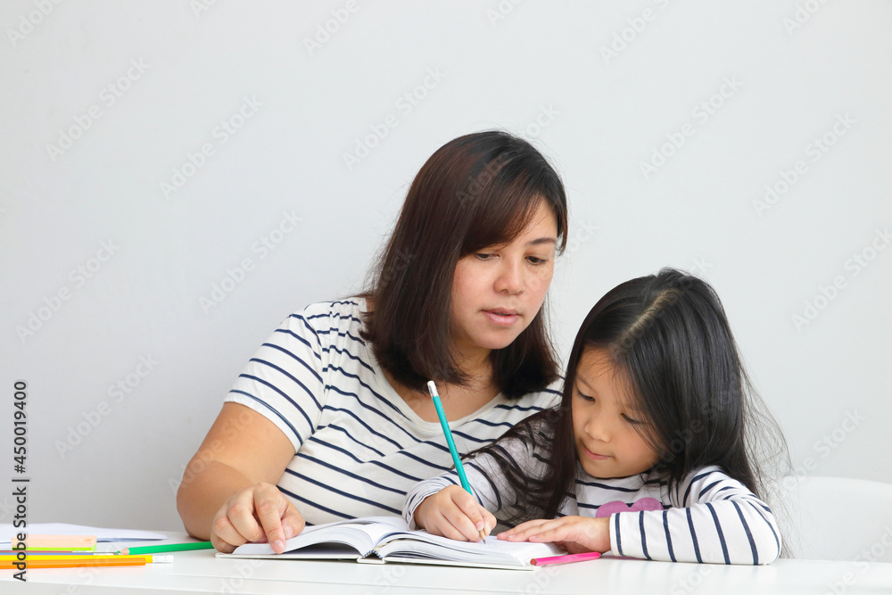 cute little asian girl Learn online from home With a mother to help teach. Education concept during the coronavirus outbreak, social distancing. cute little asian girl Learn online from home With a mother to help teach. Education concept during the coronavirus outbreak, social distancing.