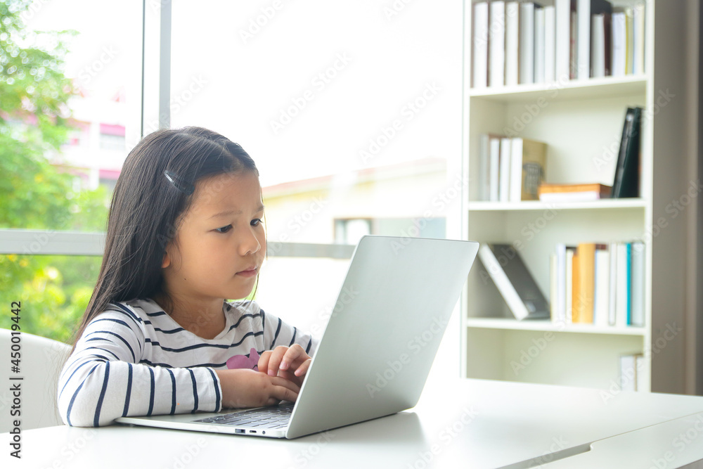 cute little asian girl Study online with teachers from home. through a laptop computer. Education concept during the coronavirus pandemic, social distancing cute little asian girl Study online with teachers from home. through a laptop computer. Education concept during the coronavirus pandemic, social distancing