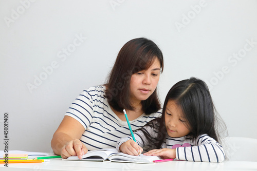 cute little asian girl Learn online from home With a mother to help teach. Education concept during the coronavirus outbreak, social distancing.