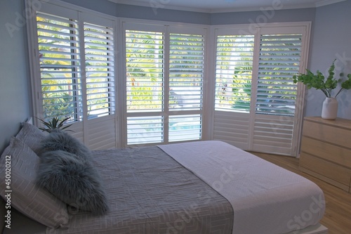 Luxury white indoor plantation shutters in bedroom - selective focus photo