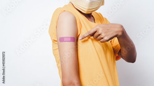 Close-up women show their arms with plaster bandages. After receiving the vaccine against COVID-19, hand pointing to plaster.