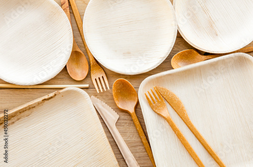 Group of dry biodegradable empty new palm leaf plates and edible fork, knife, spoon and bamboo straw. Perfect zero waste tableware for garden party. Flat lay view.