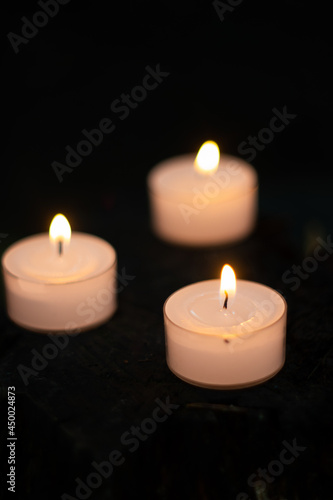 3 small burning candles close up shot  shallow depth of field  dark background