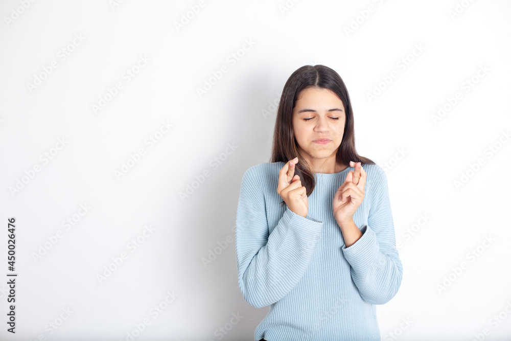 Funny teenage girl made a wish and crossed her fingers for good luck. White background, space for text. Funny teenage girl made a wish and crossed her fingers for good luck. White background, space for text.