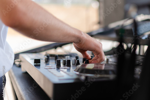 DJ playing music at outdoor event. Person operating mixer at music festival. Close up shot of deejay mixing at the party