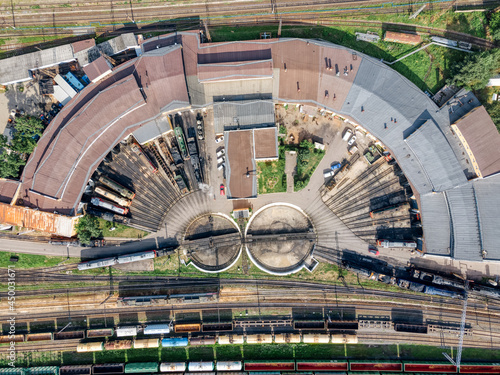 Aerial photo from the top of semicircular railway depot. Near round railway turntable for turning wagons. On railway tracks are tanks and a dump truck. Drone photoshot. Cargo transportation concept.