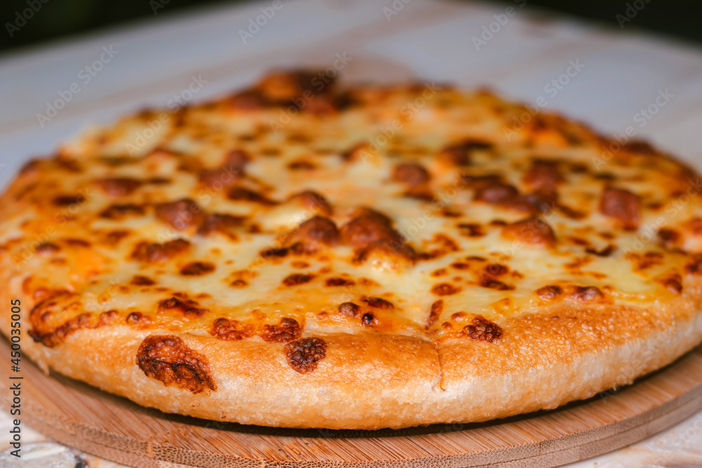 Closeup selective focus of the ready to eat pizza on a wooden tray on a wooden table. Closeup selective focus of the ready to eat pizza on a wooden tray on a wooden table.