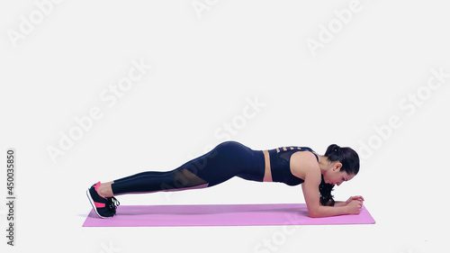 brunette young sportswoman doing plank exercise on pink fitness mat on white