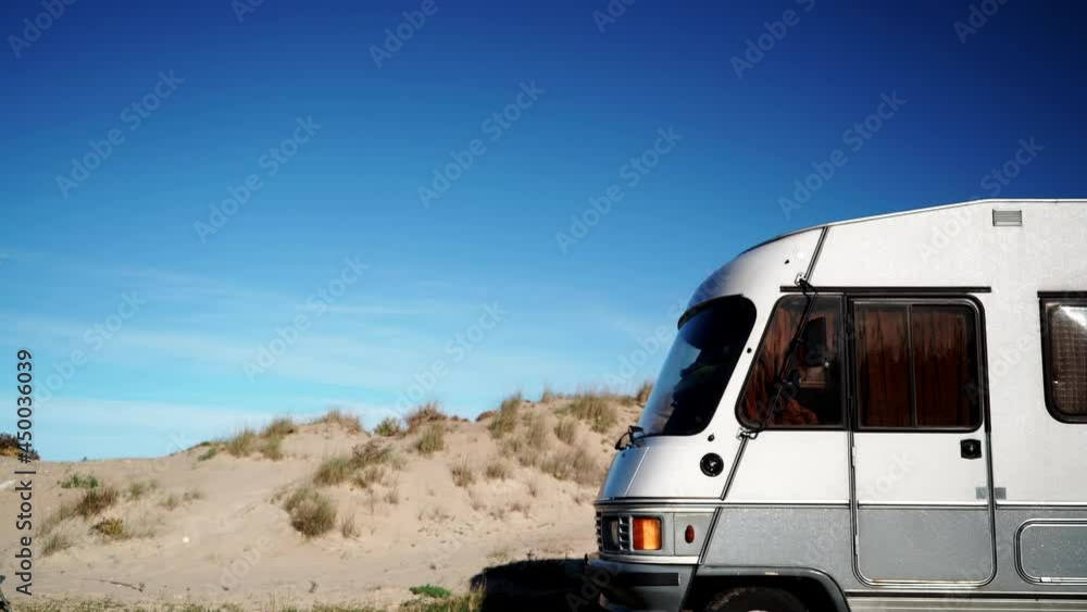 Camper vehicle on beach at dune and clouds moving across blue sky. Time lapse. Caravan vacation in Spain Camper vehicle on beach at dune and clouds moving across blue sky. Time lapse. Caravan vacation in Spain
