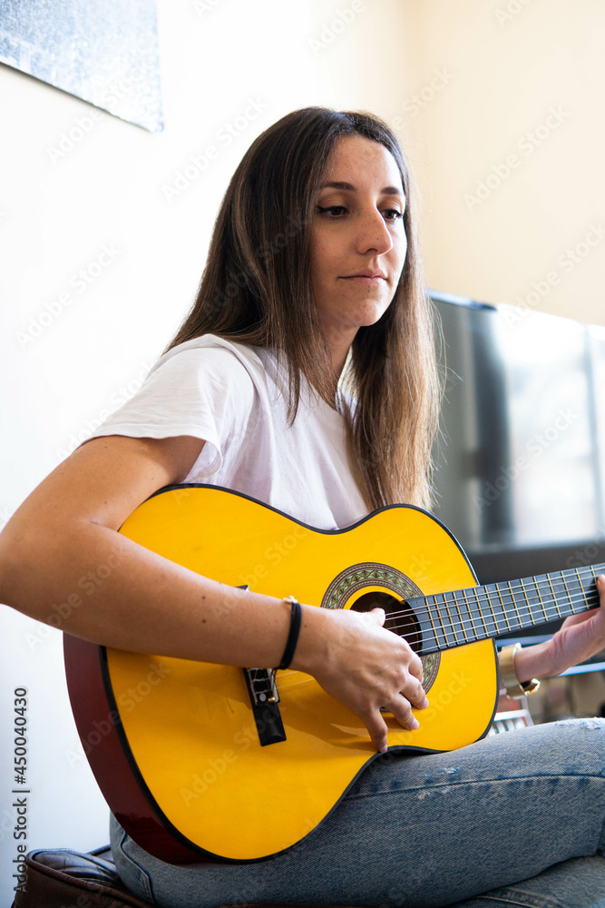 Music Concepts. Latin girl playing guitar. Latin girl relaxing with music. Latin woman have a happy lifestyle. Beautiful Latin girl playing guitar at home.