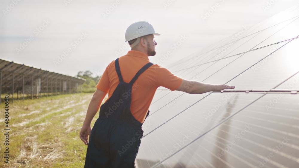 Assistance technical worker in uniform is checking an operation and efficiency performance of photovoltaic solar panels. Concept of electricity, ecology. Farm of solar panels. Green energy Assistance technical worker in uniform is checking an operation and efficiency performance of photovoltaic solar panels. Concept of electricity, ecology. Farm of solar panels. Green energy