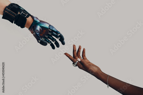 Male hand prosthesis cyborg reaching to female human black african hand. Hands touching progress concept photo